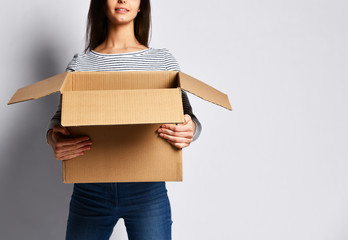 beautiful brunette woman standing on a light background with a moving cardboard box