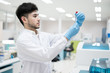 © arcyto - Portrait scientist man holding test tube and standing with automatic machine in laboratory.Researcher analysis blood chemistry in medical laboratory. Medical healthcare technology research concept.