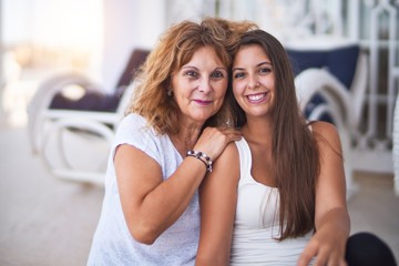 Wall Mural - Beautiful mother and daugther sitting at terrace hugging and smiling