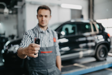 Wall Mural - Mechanic handling keys of a car at the service garage