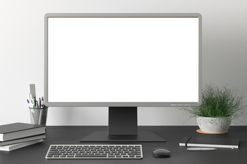 Workspace with blank computer monitor white screen mock up on the dark desk near white wall. monitor; screen; computer; mock up;