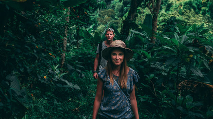 couple walking in a green jungle. Women with a hat, men with a backpack in Tanzania Africa