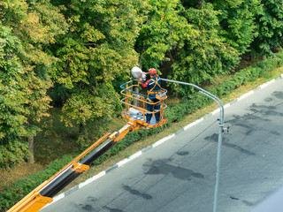 The specialist performs work on replacing old lamps on lampposts with new led lamps.