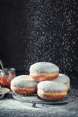 Homemade donuts on cooling grate on dark table