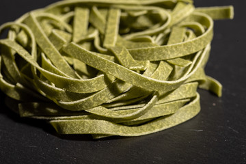 Uncooked green tagliatelle pasta, one nest, macro close up