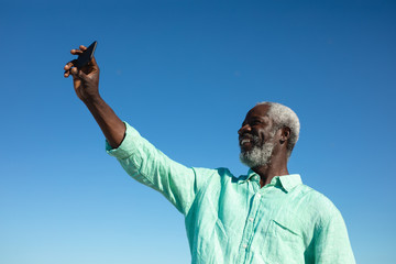 Wall Mural - Old man taking selfies at the beach