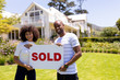 © WavebreakMediaMicro - Happy young african american couple in the garden holding sold sign