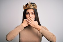 Young Beautiful Brunette Woman Wearing Golden Queen Crown Over Isolated White Background Shocked Covering Mouth With Hands For Mistake. Secret Concept.