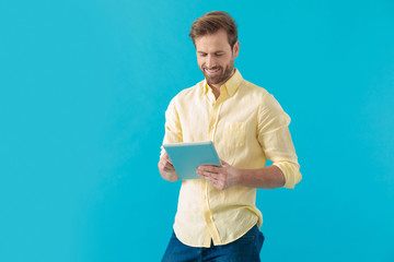 Wall Mural - Joyful casual man smiling and writing on his tablet