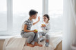 © Andrii - Brother and sister are sitting on the windowsill playing and eating apples. Happiness