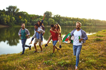 Wall Mural - Friends have fun running along the lake on a picnic.