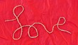 Love spelled out in string on wrinkled red paper