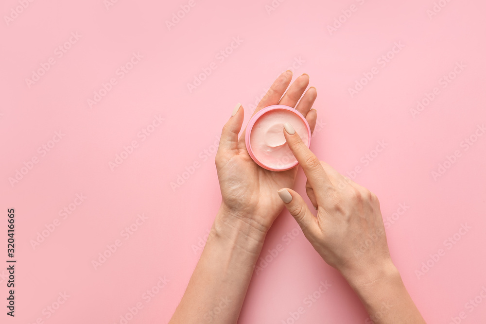 Female hands with jar of cream on color background