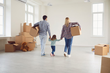 Happy family with children moving with boxes in a new apartment house.