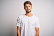 Young handsome man with beard wearing casual t-shirt standing over white background Relaxed with serious expression on face. Simple and natural looking at the camera.
