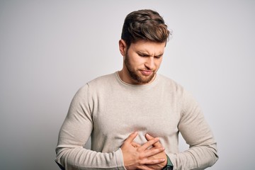 Young handsome blond man with beard and blue eyes wearing casual sweater with hand on stomach because indigestion, painful illness feeling unwell. Ache concept.