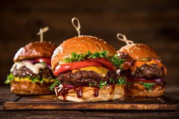 Close-up of home made tasty burgers on wooden table.