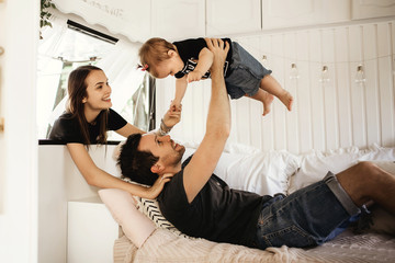 husband and wife play with their child, dad, mom and daughter, a woman holds her daughter by the hand, a very cheerful and beautiful family