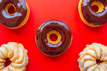 Wall Mural - Chocolate Dip Donuts with Honey Cruller Donuts on a red background