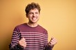 © Krakenimages.com - Young blond handsome man with curly hair wearing casual striped sweater excited for success with arms raised and eyes closed celebrating victory smiling. Winner concept.