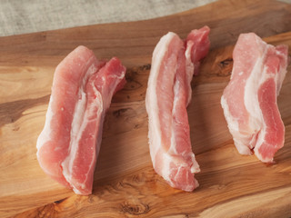 Fresh tasty uncooked pork belly slices on a wooden cutting board. Selective focus. Warm tone.