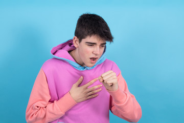 Canvas Print - portrait of young teenage man isolated on blue background coughing