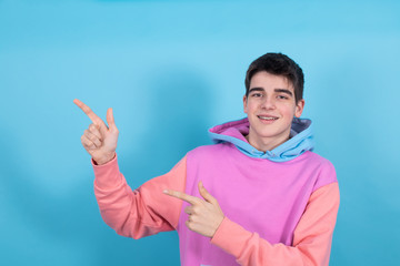 Poster - portrait of young teenage man isolated on blue background pointing out