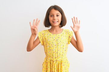 Sticker - Young beautiful child girl wearing yellow floral dress standing over isolated white background showing and pointing up with fingers number nine while smiling confident and happy.