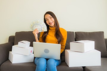 Portrait young asian woman using laptop computer for work with parcel box