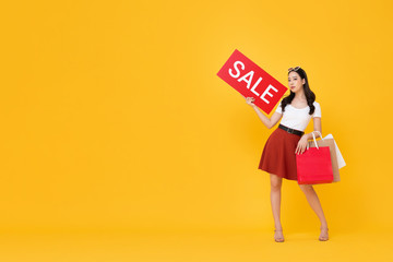 Beautiful Asian woman with shopping bags showing red sale sign