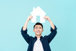 Happy young Asian man holding house sign overhead
