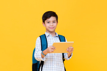 Handsome young boy in backpack holding a tablet