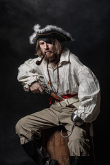 Wall Mural - medieval bearded pirate with a sword and gun. concept photo of handsome man in a pirate vintage costume with pistol and saber