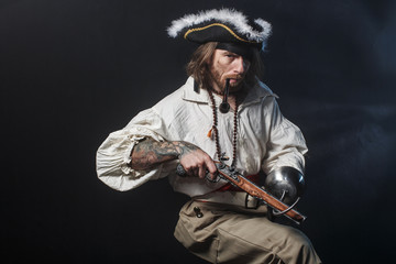 Wall Mural - medieval bearded pirate with a sword and gun. concept photo of handsome man in a pirate vintage costume with pistol and saber