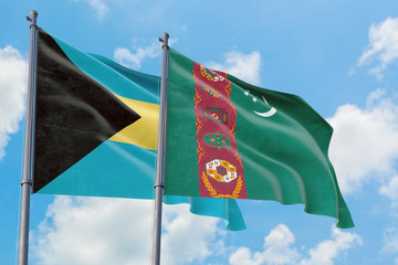 Turkmenistan and Bahamas flags waving in the wind against white cloudy blue sky together. Diplomacy concept, international relations.
