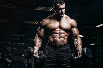 muscular man bodybuilder training in gym and posing. fit muscle guy workout with weights and barbell