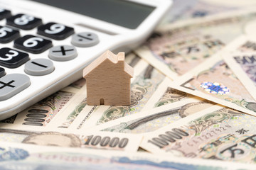 Close up little wooden house and calculator on japanese currency yen money banknote. Background concept for japan  real estate industry economy.