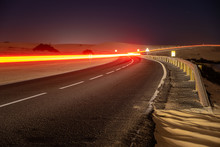 Asphalt Road Running Through The Sandy Desert At Night