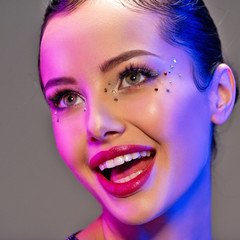 Portrait of happy girl. Laughing face of a beautiful model. Colorful portrait of a girl with bright makeup. Shiny sequins on the face. Art portrait. Happy woman. Young positive girl in a bright image.