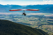 Hang glider guy flying over the Candian valley mountains on a beautiful sunny day. Extremal sportsman enjoying skydiving