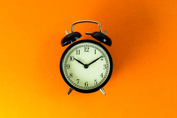 old vintage alarm clock on orange background