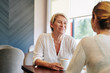 © DragonImages - Smiling pretty mature woman looking at her adult daughter telling news when thay are meeting in cafe