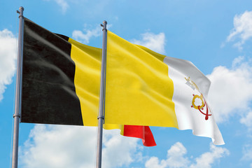 Vatican City and Belgium flags waving in the wind against white cloudy blue sky together. Diplomacy concept, international relations.