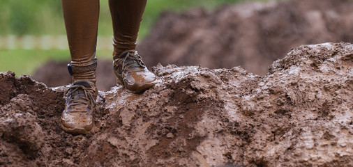 Wall Mural - Mud race runners detail of the legs, muddy running shoes a run in the mud