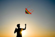 © ruslanshug - active healthy sport male holding kite flying in blue yellow sunset sky during leisure outdoor activity