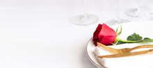 Red Rose On White Plate With Gold Cutleryon The Table In Interior Of Restaraurant. Saint Valentines Day Celebration Or Romantic Dinner Concept.Large Background For Banner