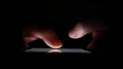man hands typing text on smartphone at night.