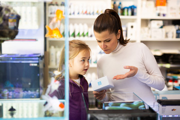 Wall Mural - Woman with girl looking for aquarium accessories in store