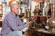 © JackF - Smiling male carefully examining antiques