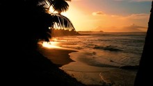 Beautiful Beach Under Orange Sunset Light With Silhouettes In The Background. Waves Break On The Sand, Aerial View, Papeete French Polynesia